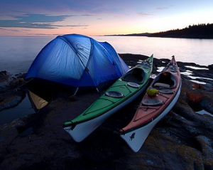 Une tente et 2 kayaks au bord de l'eau au crépuscule